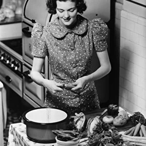 Young woman preparing vegetables in kitchen, (B&W), elevated view