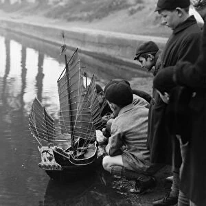 Group of boys play with a model ship in Chislehurst Kent