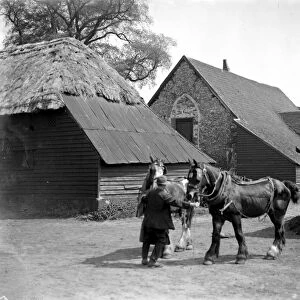Man holding two shire horses in front of a Barn Church. 1934