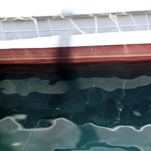 Detail of painted boat at water line showing reflections and ripples credit: Marie-Louise