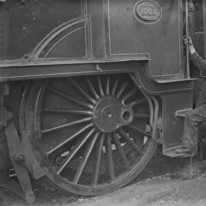 A train engineer looks at one of the large engine wheels after being derailed at Swanley