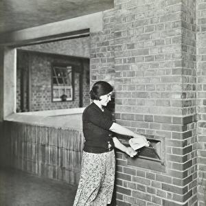Ossulston Estate: woman emptying rubbish into a chute, 1936 (b / w photo)