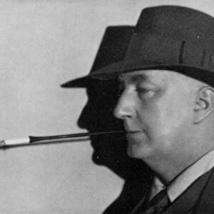 Portrait of Edgar Wallace, wearing hat and smoking cigarette in holder (b / w photo)