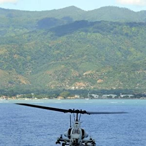 An AH-1W Super Cobra flies off the coast of Dili, East Timor
