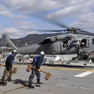 Airmen prepare to chock and chain an MH-60S Sea Hawk helicopter