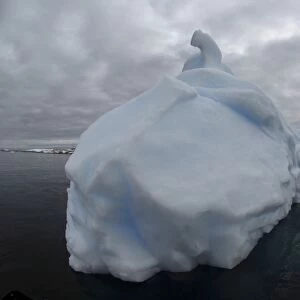 Floating iceberg with grey sky and black sea, Antarctica