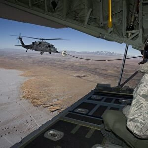 A loadmaster on an HC-130 watches as an HH-60G Pave Hawk refuels
