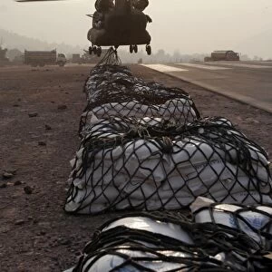 Marines attach sling loads to the body of an Army CH-47 Chinook cargo helicopter