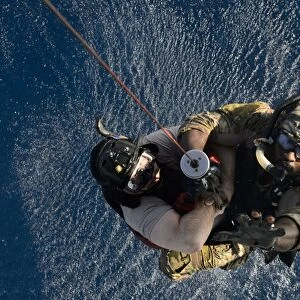 A pararescueman and rescuee are hoisted into an HH-60G Pave Hawk