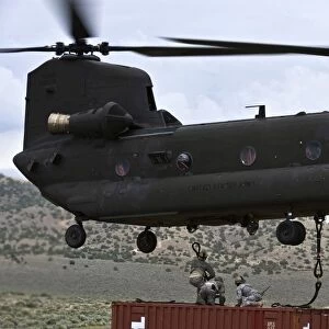 Personnel attach a storage container to a CH-47 Chinook helicopter