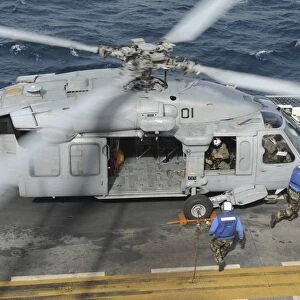 Personnel remove chock and chains from an H-60 Sea Hawk helicopter