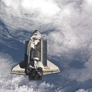 Space shuttle Atlantis above a cloud covered Earth