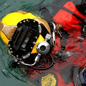 U. S. Navy Diver is lowered into the water during a pier repair operations dive