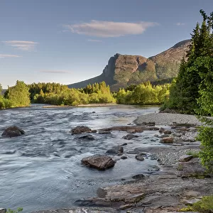 The Hemsila river in summer, tree-lined riverbanks and hills with high cloud in sky, Hemsedal region, Norway. June, 2022