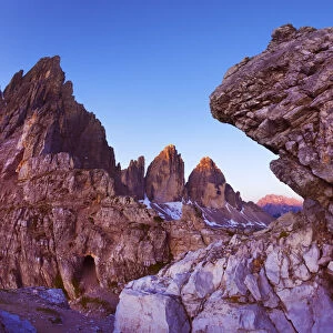 Paternkofel (left) and Tre Cime di Lavaredo mountains at dawn seen behind rocks, Sexten Dolomites