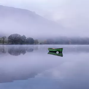 Rowing boat on Ullswater in early morning mist, Lake District, Cumbria, England, UK. November 2015