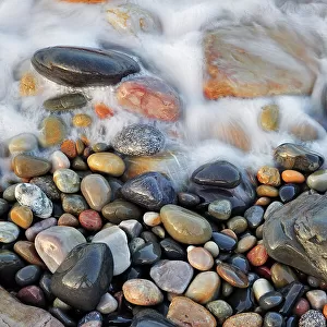Sea surf washing over colourful water-smoothed pebbles, Normandy, France, October 2010