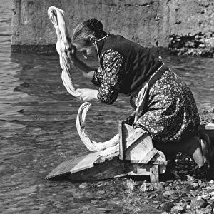 Woman washing clothes in a river, Portugal, 1973