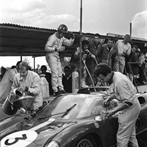 1964 Tourist Trophy: Graham Hill, 1st position, in the pits for fuel and a drink, portrait
