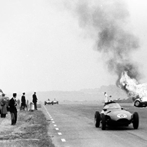 Silverstone, Great Britain. 14 July 1956: Tony Brookss BRM P25 burns after he had crashed as the car of Harry Schell, Vanwall VW2, retired