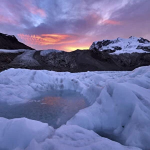 Frozen pool of water on the ice of the Gorner Glacier at sunrise