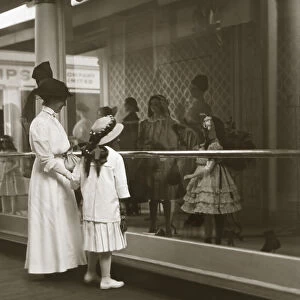 Mother and daughter looking in shop window in Victorian or Edwardian era in sepia tone