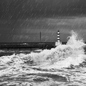 Rainfall And Splashing Waves With A Lighthouse Along The Coast; Amble, Northumberland, England