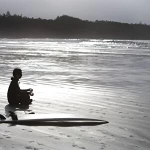 Surfer Meditating On Beach, Cox Bay Near Tofino, British Columbia, Canada