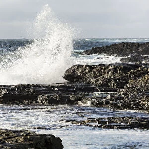 Wave Crashing Into Rocky Coast With Cloudy Sky; Kilkee, County Clare, Ireland