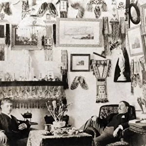 Two young men in a bachelors parlour in Victorian times with trophies hanging on wall; England
