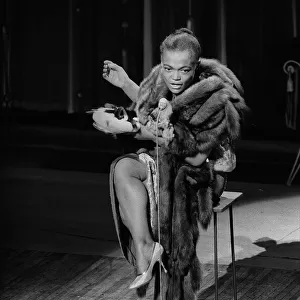 American actress and singer Eartha Kitt warms up that sultriest of voices during a dress