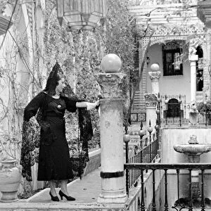 An Andalusian woman wearing black veil and standing on a balcony in Seville