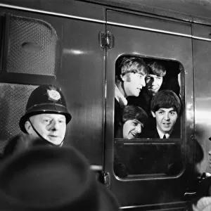The Beatles peer from a train carriage window at Paddington Station, London