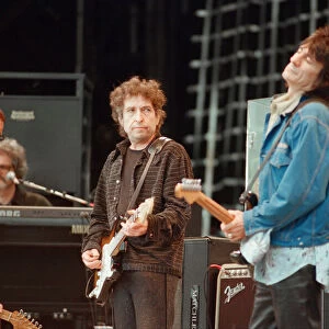 Bob Dylan (left in brown clothing) looks over at Ronnie Wood (in blue