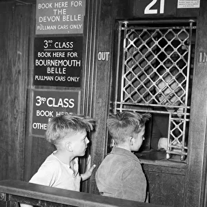 Two boys buying a ticket from the booking office at London