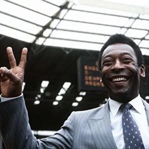 Brazillian football legend Pele gives the peace sign while standing on the pitch at