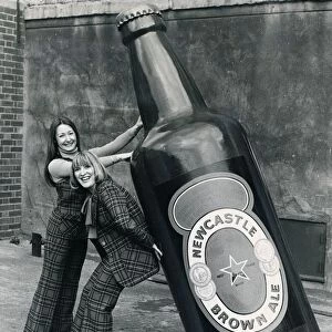 Brenda Kelly (without jacket) and Jennifer Donkin holding a nine foot tall bottle of