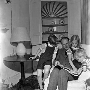 Brigadier Fitzroy Maclean looking through a copy of Life with his children Jeremy