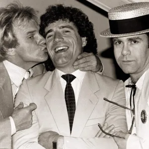 Comedian Freddie Starr kisses England striker Kevin Keegan as Pop star Elton John looks