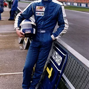 David Coulthard leaning on fence at race track holding helmet racing Formula 3000