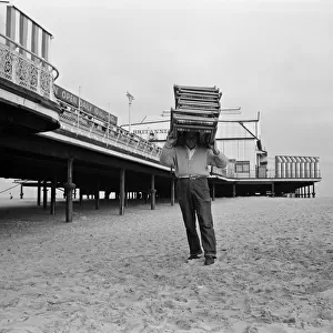 A deck chair attendant carrying deck chairs on his head. Great Yarmouth, Norfolk