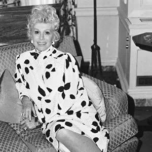 Eva Gabor Actress sitting on sofa in black and white patterned dress June 1983