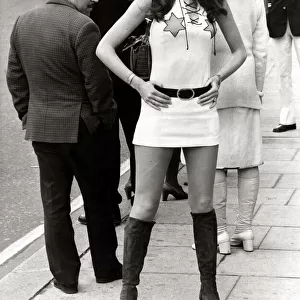 Female model Beulah Hughes wearing a mini dress and knee high boots in a London street as