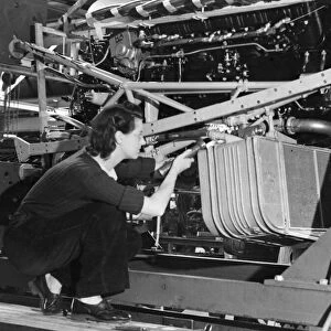 A female worker inspecting the cooling system of a Lancaster bomber plane of the Royal