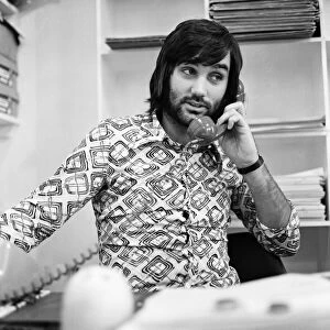 Footballer George Best, business man on the phone sitting at desk in his shop
