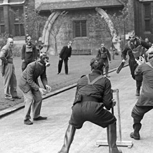 A game of cricket played in an English village by men wearing gas masks May 1941