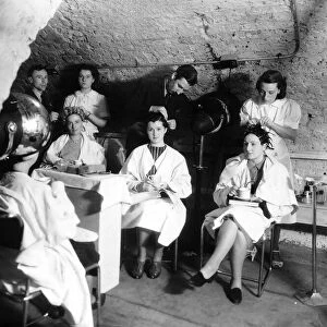 Hairdressers carry on working in an underground air raid shelter during WW2