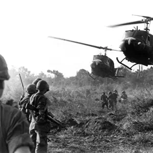 HUEY HELICOPTERS LAND IN FIELD DURING THE VIETNAM WAR TO PICK UP CASUALTIES SUSTAINED BY