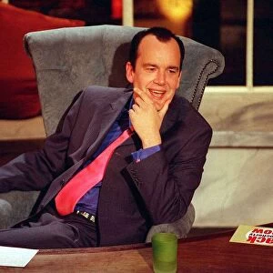 Jack Docherty sitting in chair next to desk in Channel 5 studio April 1997