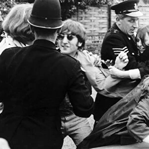 John Lennon is mobbed by fans as police try to escort the teenage girls away after
